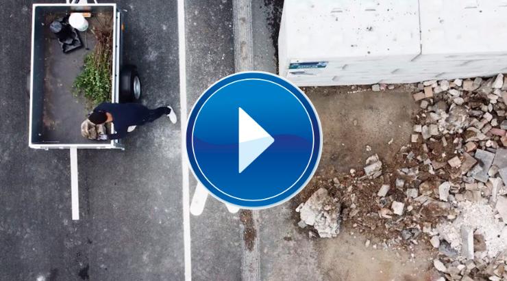 Person læsser affald af fra trailer på genbrugsplads + stort video ikon play