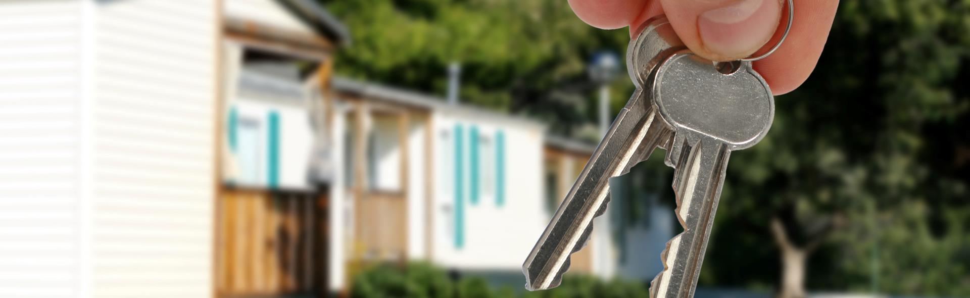 Indberet flytning Hånd holder to nøgle med hus i baggrunden