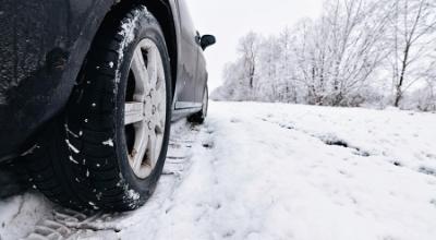 Bil kører på snebelagt vej