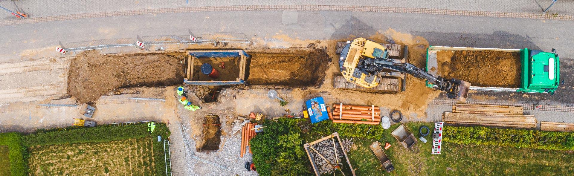 Gravemaskine graver jord fra vej og smider det op i ladet på lastbil