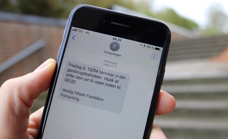 Mobiltelefon med sms-påmindelse vedrørende tømning af genbrugsbeholder