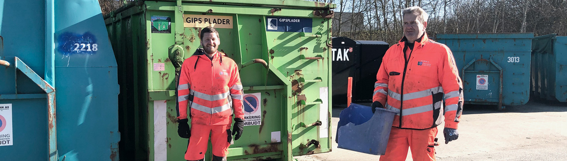 to glade pladsmænd i orange arbejdstøj smiler på genbrugsplads