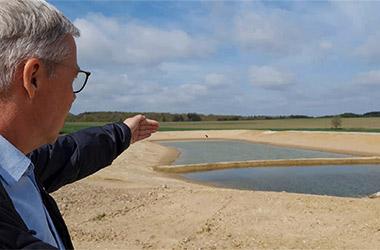 Mand peger ud på anlægsarbejde af etablering af regnvandsbassin