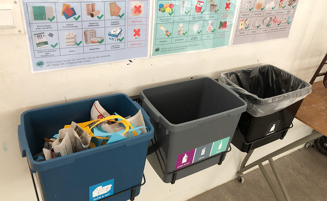 Spande til sortering af affald hænger på væg i skole