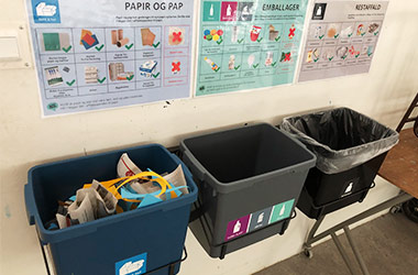 Tre spande til affaldssortering hænger på væg i skole